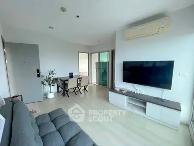 Modern living room with sleek furniture and large TV, featuring minimalist design and natural light.