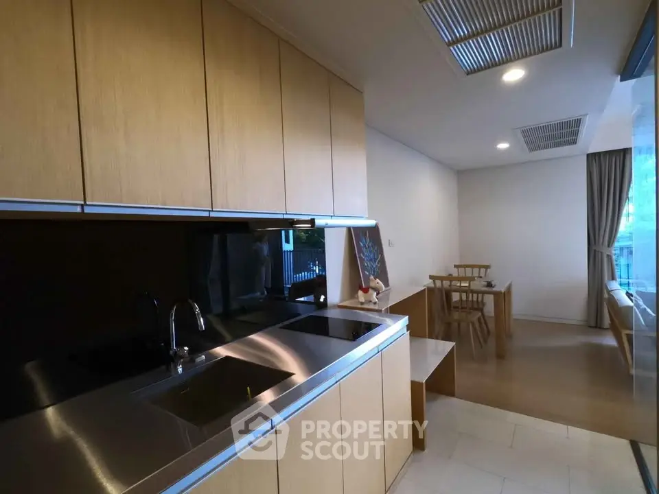 Modern kitchen with sleek cabinetry and dining area in open layout apartment.
