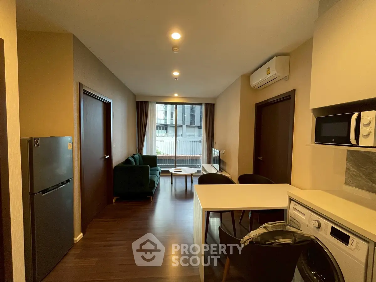 Modern apartment interior with open kitchen and cozy living area, featuring sleek appliances and stylish decor.
