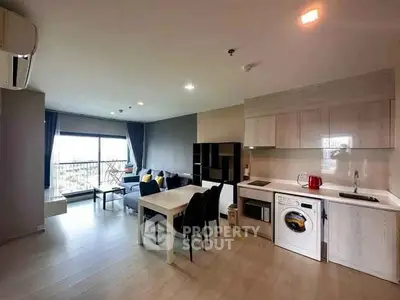 Modern open-plan living room with kitchen, featuring large windows and stylish furniture.