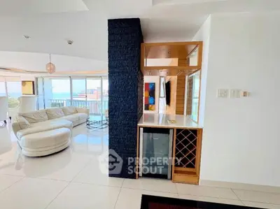 Luxurious living room with modern design and stunning ocean view, featuring elegant furniture and a mini bar.
