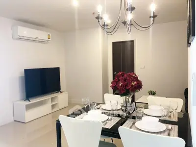 Modern living room with elegant dining setup and flat-screen TV.