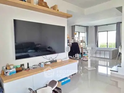 Spacious modern living room with large TV and bright natural light