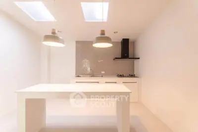 Modern minimalist kitchen with sleek design and open layout, featuring skylights and stylish lighting.