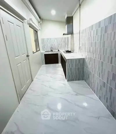 Modern kitchen with sleek design, featuring tiled walls and marble flooring, perfect for culinary enthusiasts.
