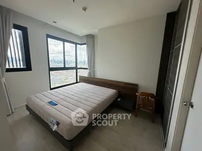 Spacious bedroom with city view and modern furnishings in high-rise apartment.
