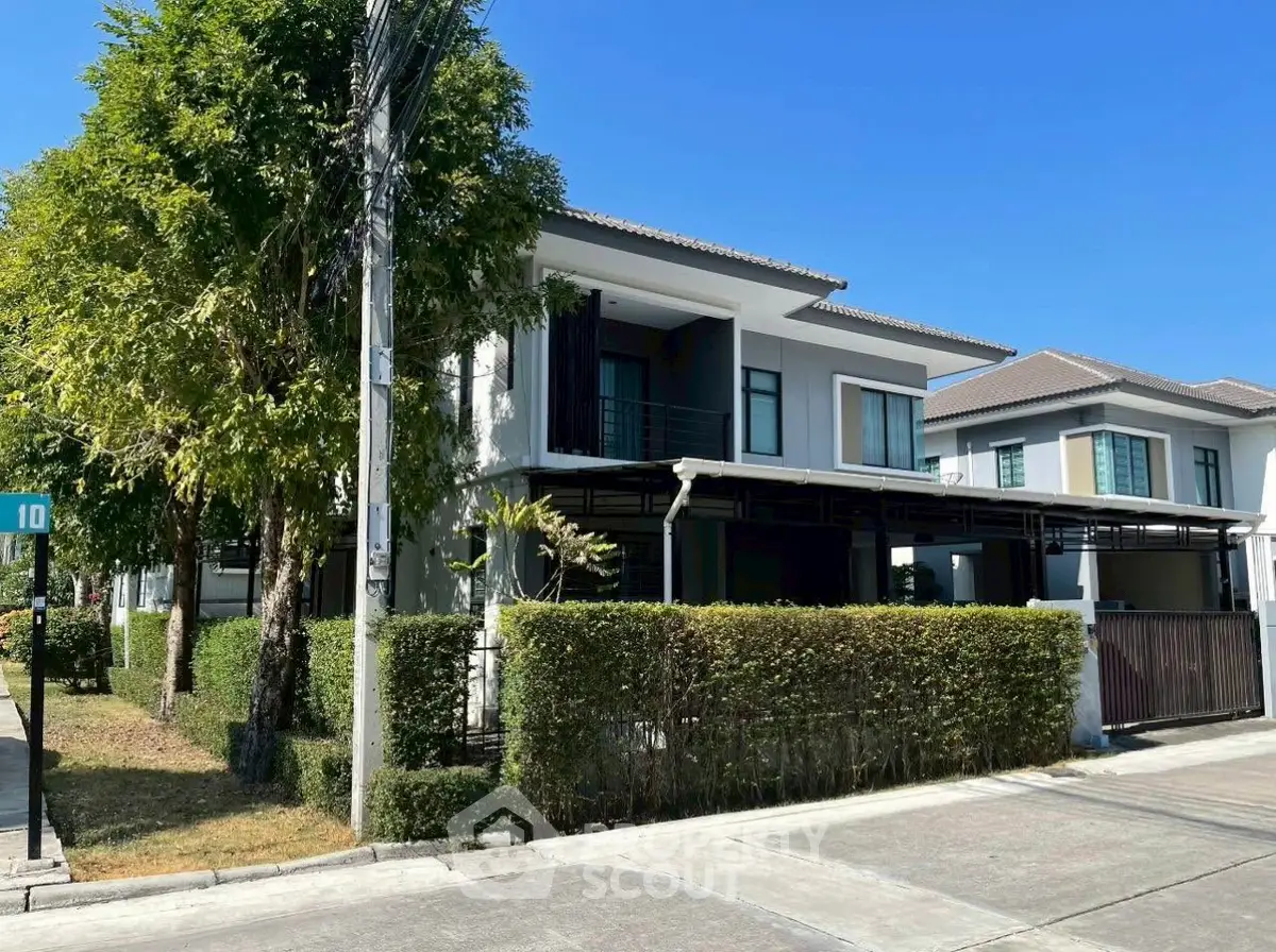 Modern two-story house with lush greenery and clear blue sky, perfect suburban living.