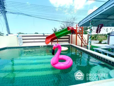 Charming outdoor pool with slide and flamingo float in a serene setting