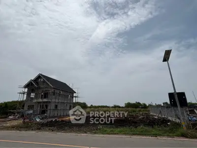 Under-construction house with scaffolding on a spacious plot, ideal for customization.