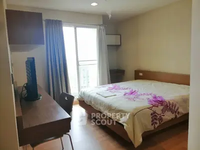 Cozy bedroom with large window and modern furnishings in a stylish apartment.