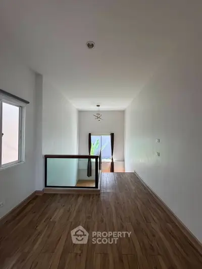 Spacious interior with wooden flooring and large window offering natural light.