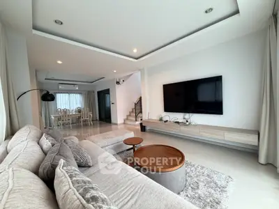 Spacious modern living room with elegant decor and large TV, perfect for family gatherings.