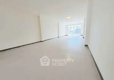 Spacious empty living room with large windows and tiled flooring, ready for customization.