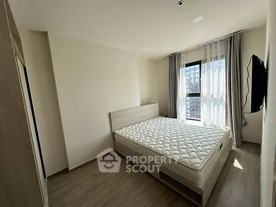 Modern bedroom with natural light and minimalist design, featuring a comfortable bed and wall-mounted TV.