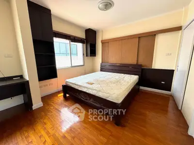 Spacious bedroom with wooden flooring and large window for natural light