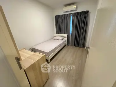 Cozy minimalist bedroom with wooden flooring and air conditioning