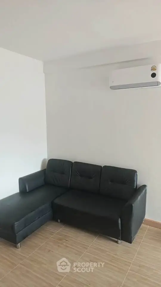 Modern living room with sleek black sofa and air conditioning, perfect for comfort and style.