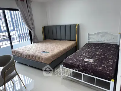 Spacious bedroom with two beds and large window offering natural light.