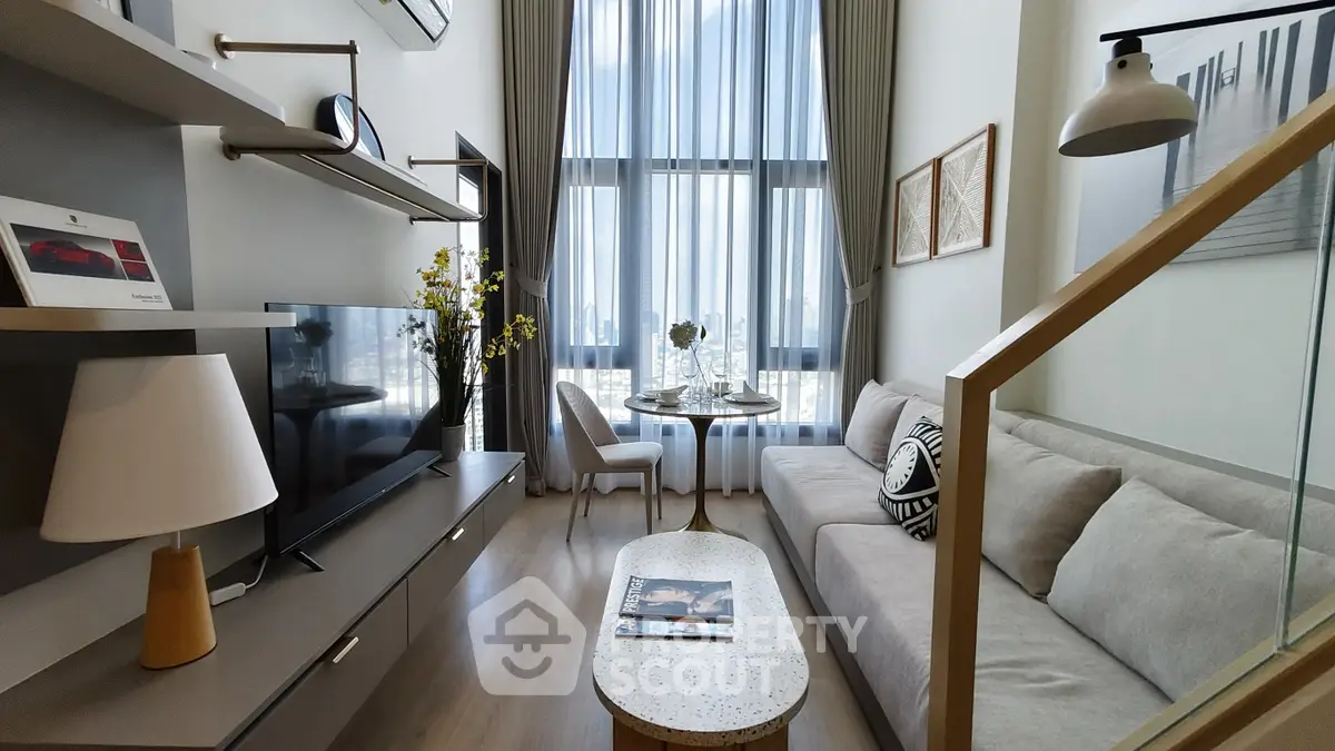 Modern living room with high ceilings, large windows, and stylish decor in a contemporary apartment.