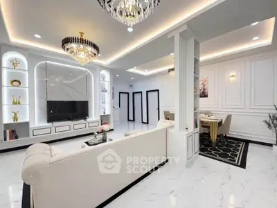 Luxurious modern living room with elegant chandeliers and open dining area, featuring sleek white decor and stylish furnishings.