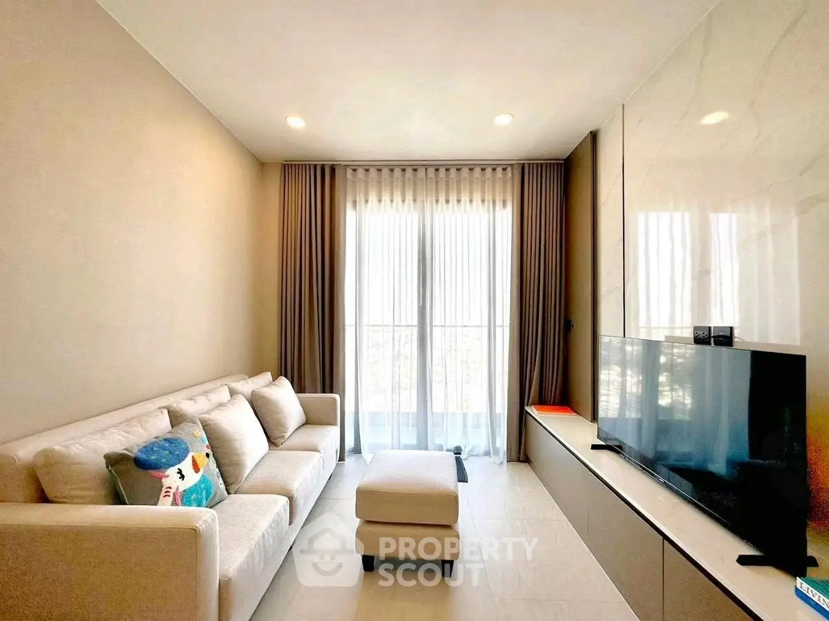 Modern living room with cozy sofa and large TV, featuring elegant curtains and bright lighting.