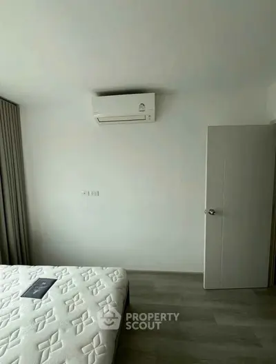 Modern bedroom with air conditioning and minimalist decor, featuring a comfortable mattress and sleek flooring.