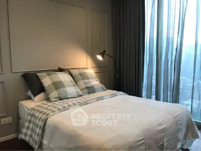 Cozy bedroom with stylish decor and city view through large windows.