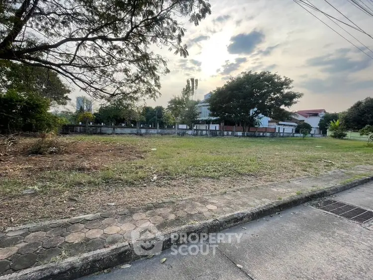 Spacious vacant land plot with lush greenery, perfect for development in a serene neighborhood.