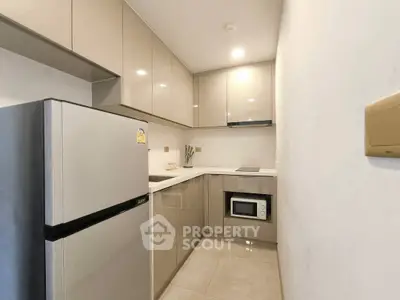 Modern kitchen with sleek cabinetry and built-in microwave in a compact layout.