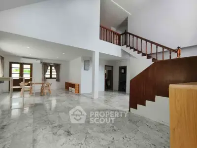 Spacious open-plan living area with elegant staircase and marble flooring