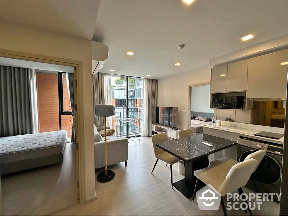 Modern open-plan living room with dining area and balcony access in stylish apartment.