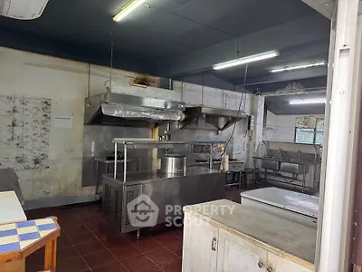 Spacious commercial kitchen with stainless steel appliances and ample workspace.