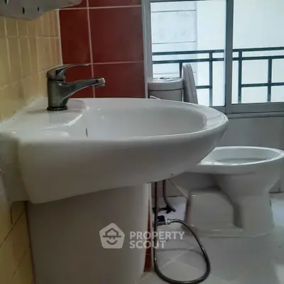 Modern bathroom with sleek sink and toilet, featuring a large window for natural light.