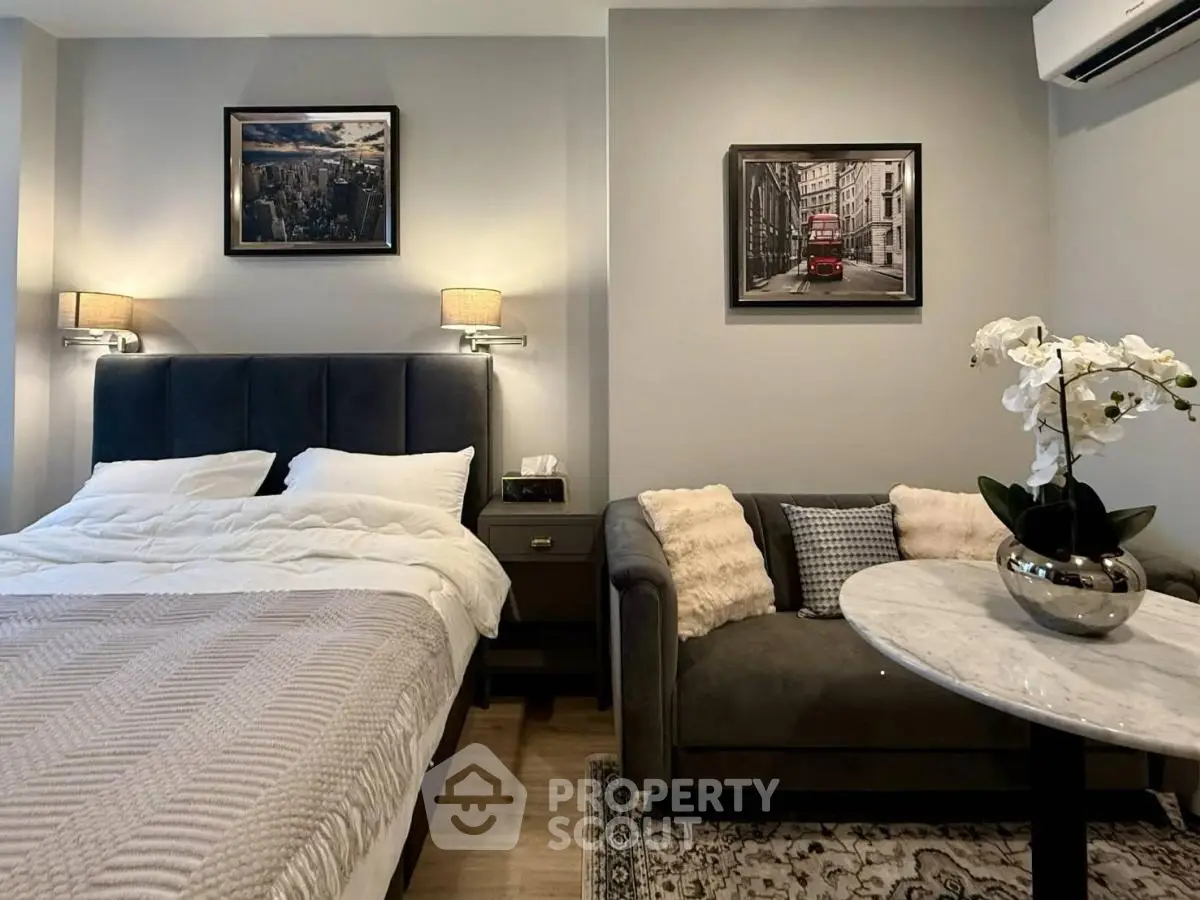 Modern bedroom with elegant decor, featuring a cozy bed, stylish sofa, and chic wall art.