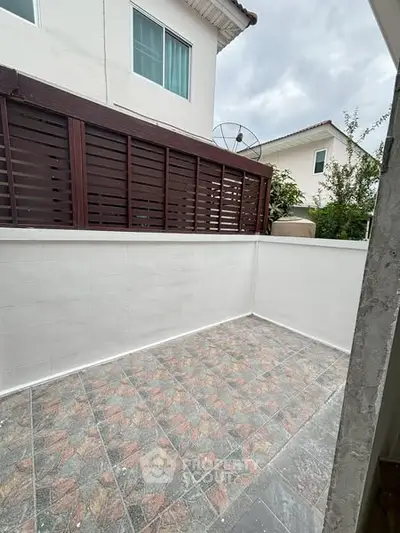 Charming small outdoor patio with tiled flooring and privacy fence, perfect for relaxation.