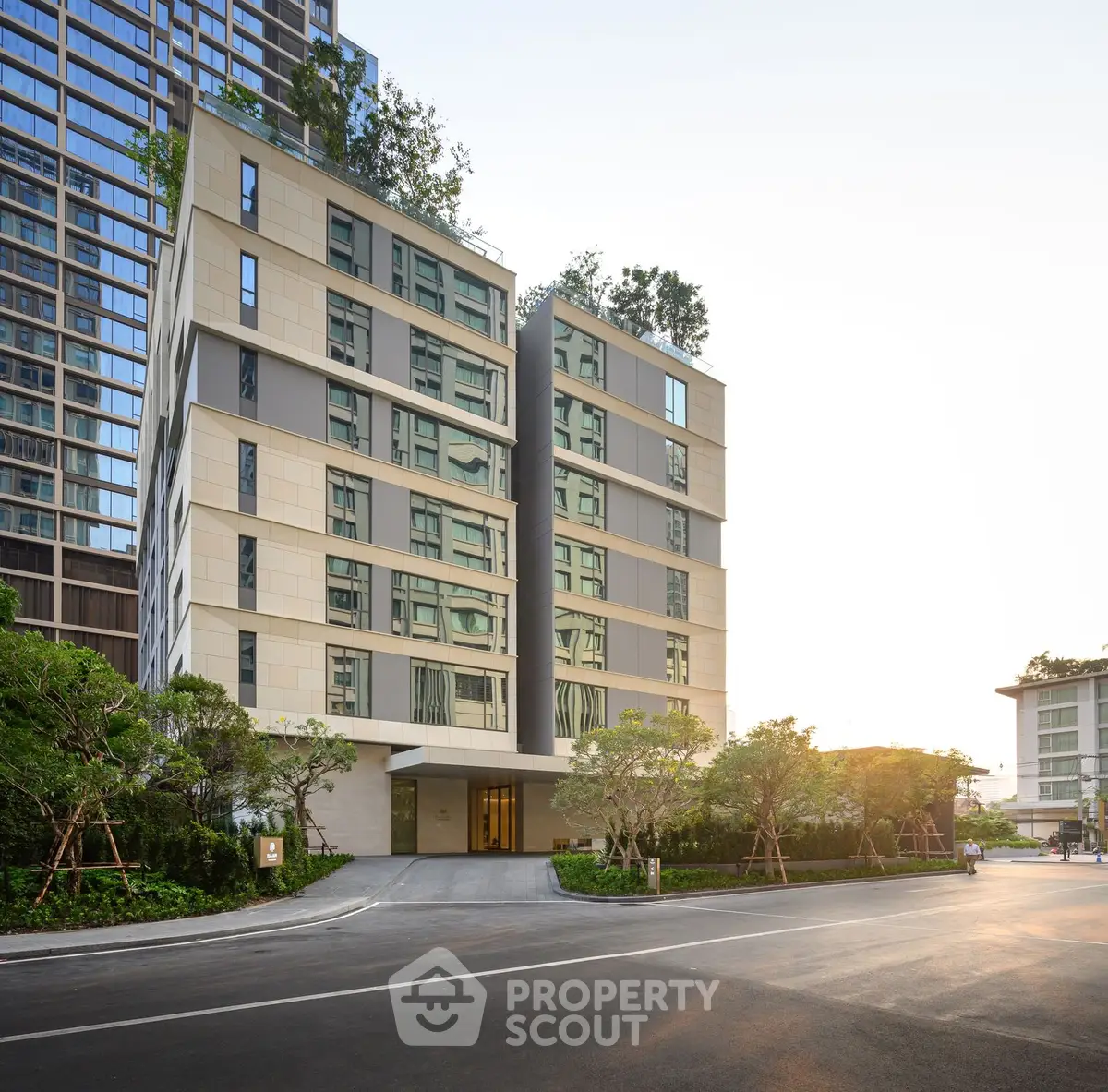 Modern apartment building with lush greenery and sleek architecture at sunset.
