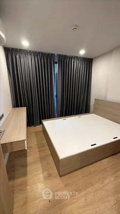 Modern minimalist bedroom with sleek wooden flooring, elegant dark curtains, and a large bed frame ready for customization.