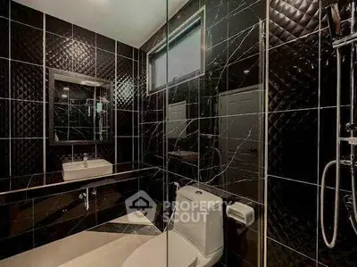 Luxurious black-tiled bathroom with modern fixtures and elegant design.