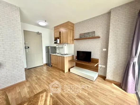 Modern studio apartment with compact kitchen and cozy living area, featuring wood flooring and natural light.