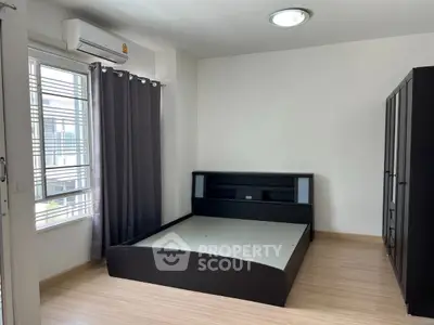 Spacious bedroom with modern bed frame and large window for natural light.
