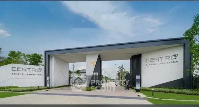 Modern gated entrance of Centro Bangna Srinakarin with sleek design and lush greenery.