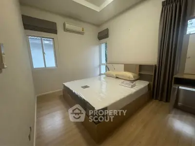 Cozy bedroom with modern design, featuring a comfortable bed and natural light from the window.