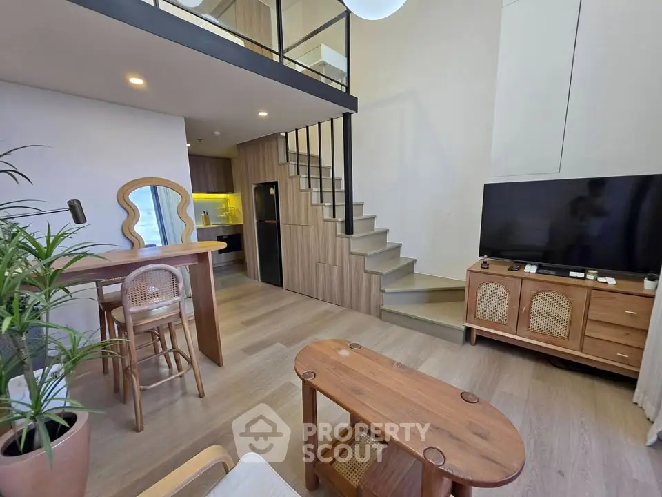 Modern loft-style living room with mezzanine, stylish furniture, and open kitchen layout.