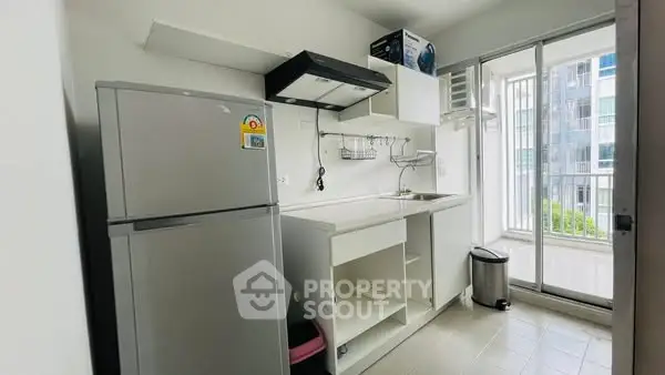 Modern kitchen with balcony view, featuring sleek appliances and ample storage space.