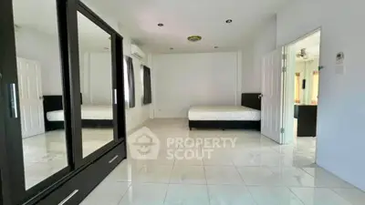 Spacious bedroom with mirrored wardrobe and tiled flooring in modern home