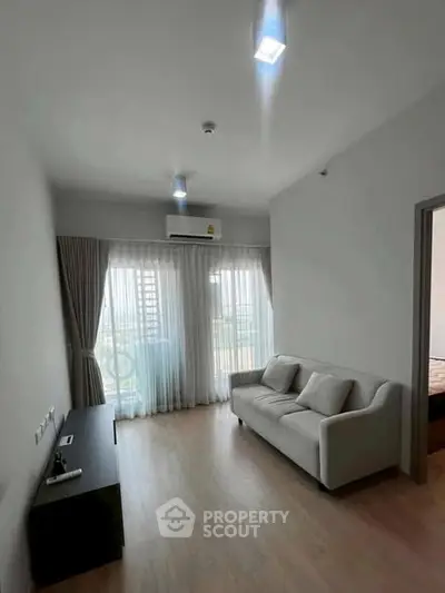 Modern living room with sleek design, featuring a comfortable sofa and large window for natural light.