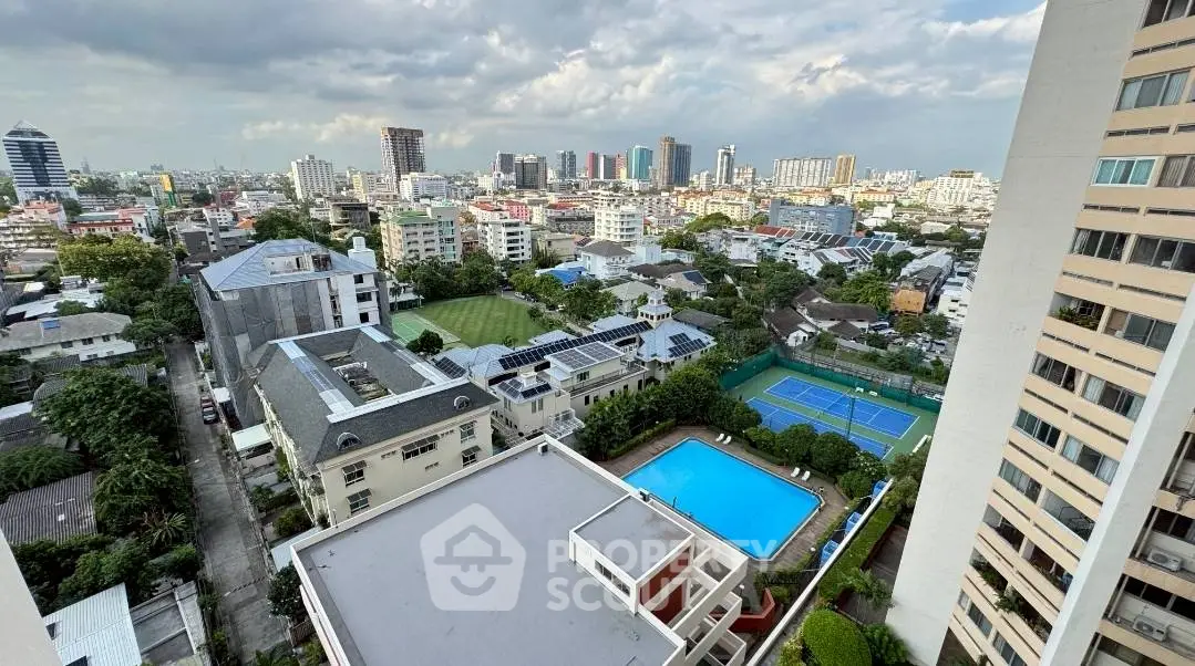 Stunning cityscape view with pool and tennis court from high-rise apartment balcony.