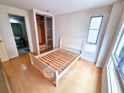 Spacious bedroom with wooden flooring and large window for natural light