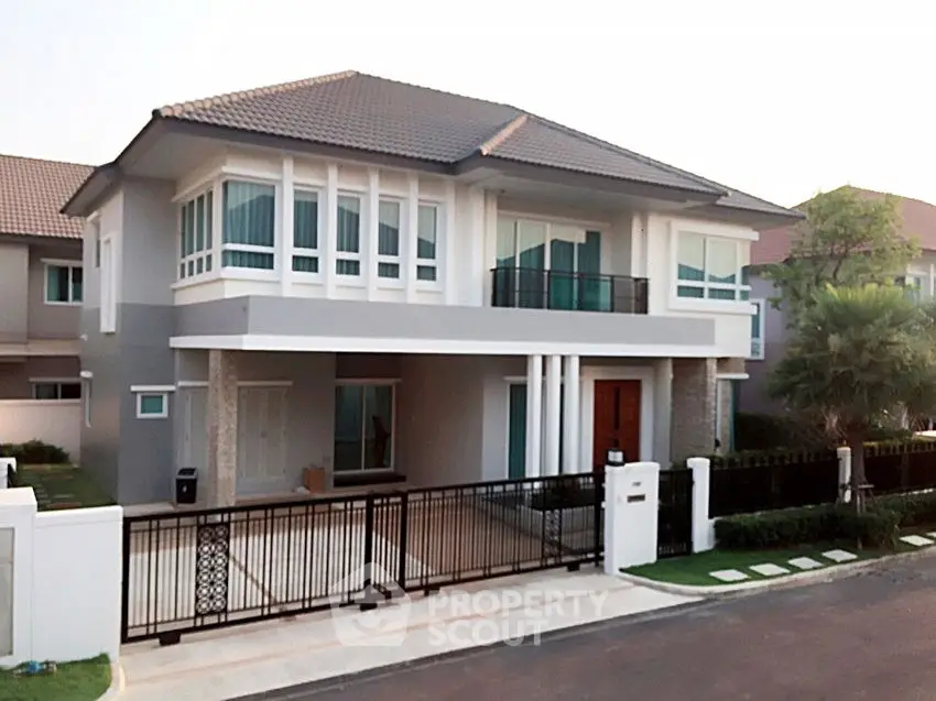 Modern two-story house with sleek design and spacious driveway in suburban neighborhood.