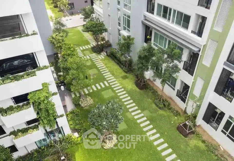 Modern apartment complex with lush green garden and pathway view
